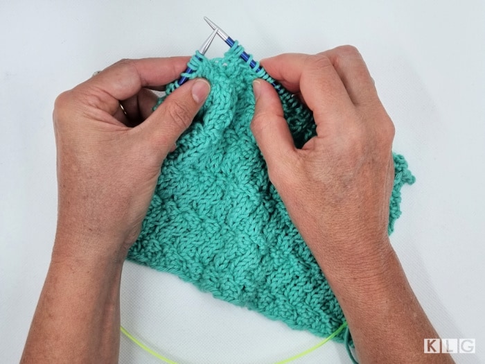 Me holding Zing Blue aluminum interchangeable needles with aqua cotton dishcloth project on the go 