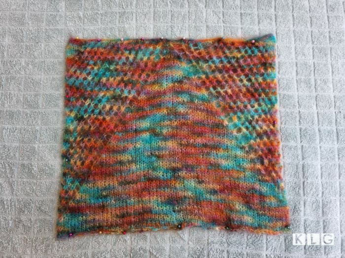 Colorful mohair cowl pinned to a towel after being immersed in water and then the water squeezed out. Part of the wet blocking process.