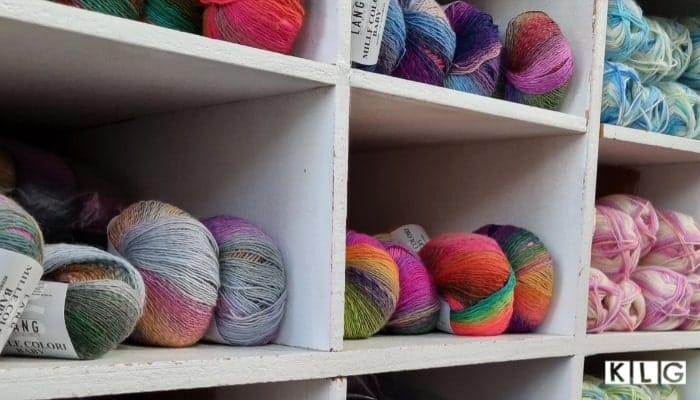 Multicolored yarn balls on white shelving