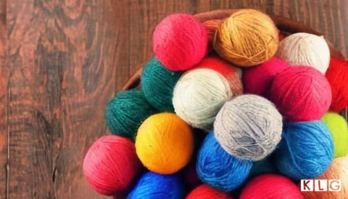A Birdseye View Of Yarn balls in different colors On A Wood Surface